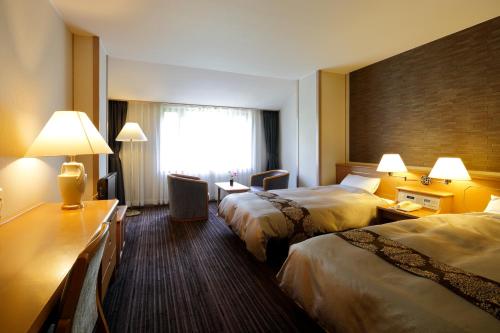 高山市にある穂高荘 山のホテルのベッド2台と窓が備わるホテルルームです。