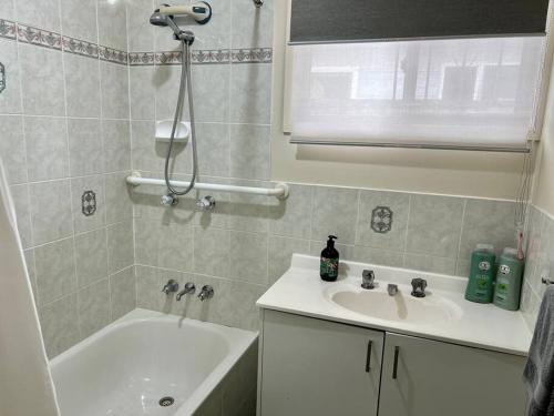 Caboolture South 3-bedroom Home في كابولتشر: حمام مع حوض وحوض استحمام ودش