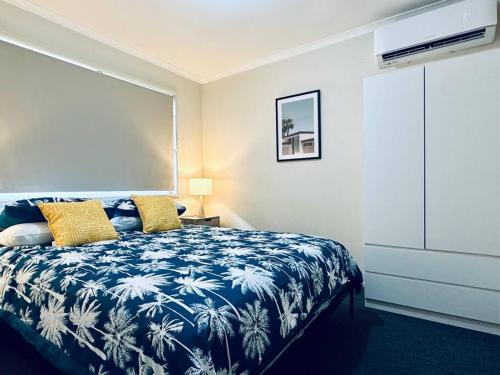 Caboolture South 3-bedroom Home في كابولتشر: غرفة نوم بسرير ازرق وبيض مع مخدات صفراء