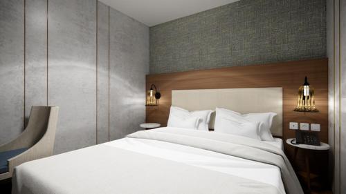 a bedroom with a large white bed and two lights at d'primahotel Airport Jakarta Terminal 3 Wellness Center in Tangerang