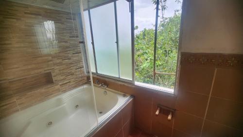 a bathroom with a bath tub and a window at Hotel spa la buena vida in Fusagasuga