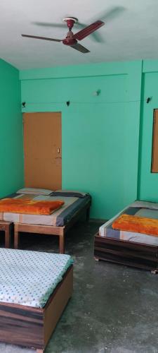 3 camas num quarto com uma ventoinha de tecto em Gomukh Home Stay em Uttarkāshi