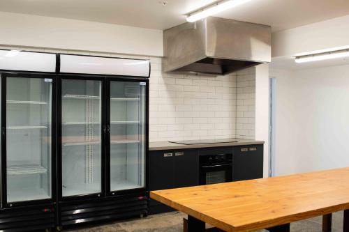 kuchnia z czarnymi szafkami i drewnianym stołem w obiekcie Bayside House w Melbourne