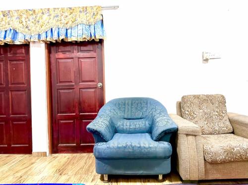 a blue recliner and a chair in front of a door at Isyfaq Homestay 2 bedroom & 2 bathroom in Kota Tinggi