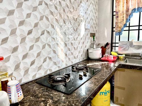 a kitchen with a stove and a counter top at Isyfaq Homestay 2 bedroom & 2 bathroom in Kota Tinggi