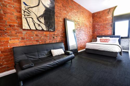 sala de estar con sofá de cuero negro y pared de ladrillo en Bayside House, en Melbourne