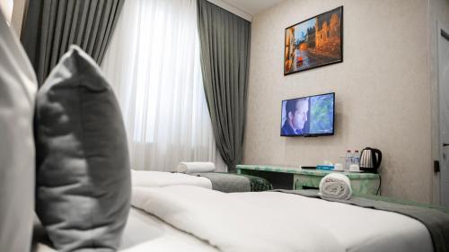 a hotel room with two beds and a television at Essam Deluxe Hotel in Baku