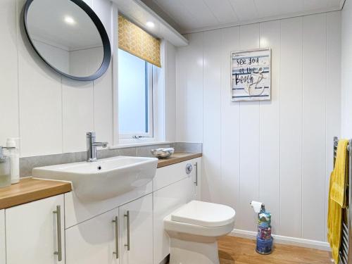 a bathroom with a sink and a toilet and a mirror at Kilda View in Berneray