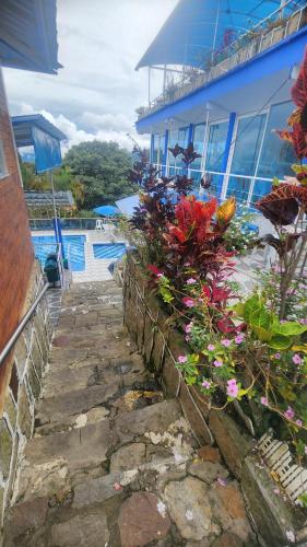 a stone path next to a blue building with flowers at Hotel spa la buena vida in Fusagasuga