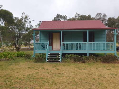 a blue house with a red roof and a porch at Drovers Retreat in Thulimbah
