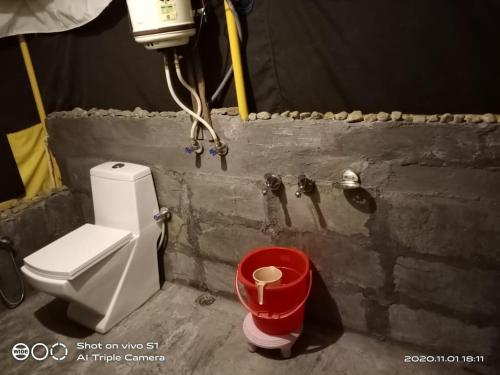 łazienka z toaletą i czerwonym koszem na śmieci w obiekcie Hideout w mieście Bir