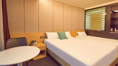 a room with two beds and a table and a table at Chuncheon Eston Hotel in Chuncheon