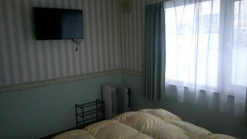 a bedroom with a bed and a television on the wall at ホテルていね in Sapporo