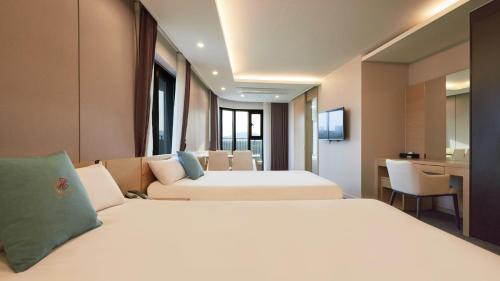 a hotel room with two beds and a desk at Chuncheon Eston Hotel in Chuncheon