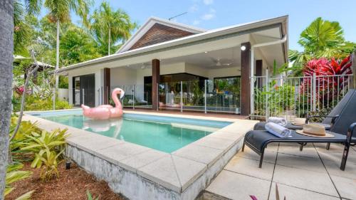 ein Schwimmbad mit einem rosa Flamingo vor einem Haus in der Unterkunft Cascade Drive Port Douglas in Craiglie