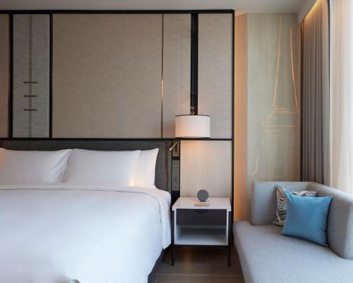 a hotel room with a bed and a chair at dusitD2 Samyan Bangkok in Bangkok