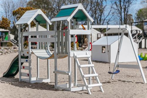 a playground with a ladder and a slide at Herbals - Tree&Lake houses with bath, sauna, bikes, motorboat in Mielno