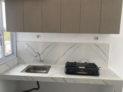 eine Küchentheke mit einer Spüle und einem schwarzen Gerät in der Unterkunft POP Exclusive - Female Only in Jakarta