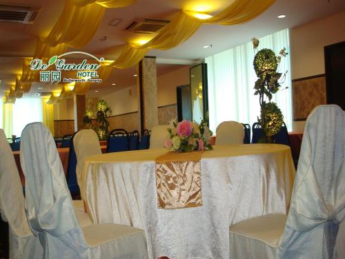a table with white chairs and a table with flowers on it at De' Garden Hotel, Butterworth in Butterworth