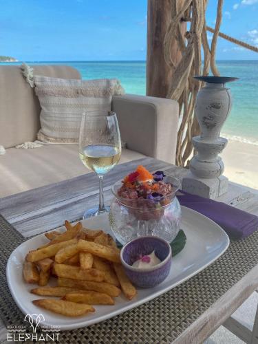 a plate of food with french fries and a glass of wine at Elephant Beach Club & Resort Samui in Chaweng