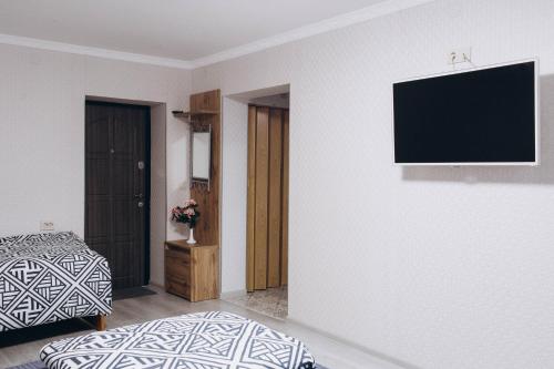 ein Schlafzimmer mit einem Bett und einem TV an der Wand in der Unterkunft Однокімнатна дизайнерська квартира поруч з термальними водами in Berehowe