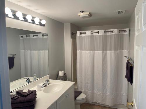 ein Badezimmer mit einem Waschbecken und einem weißen Duschvorhang in der Unterkunft Water Street Retreat 04 in Wilmington