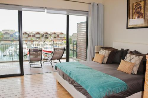 a bedroom with a bed and a balcony with a table and chairs at La Balise Marina by Horizon Holidays in Tamarin