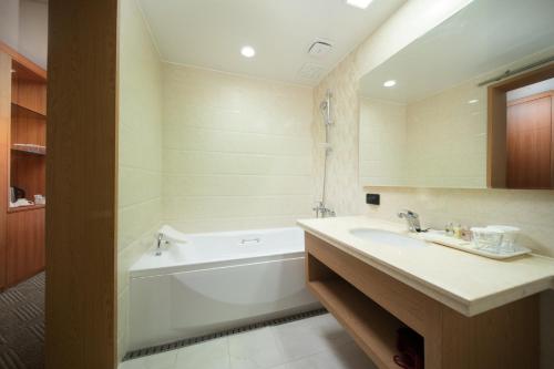 a bathroom with a bath tub and a sink and a bath tub at Bareve Hotel in Seogwipo