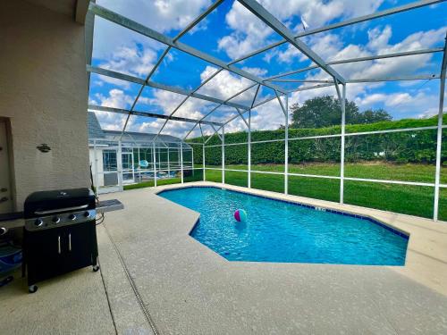 einen Pool in einem Haus mit Glasdach in der Unterkunft Grand Superior 4BR Pool House near Disney Parks in Davenport