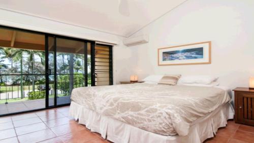 um quarto com uma cama e uma grande janela em On The Beach 3 Port Douglas em Port Douglas