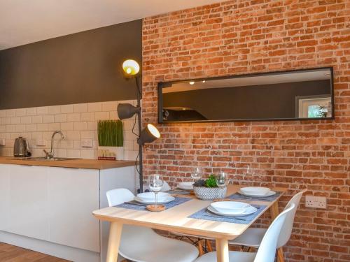 a dining room table with white chairs and a brick wall at River Lodge Annexe in Rhondda