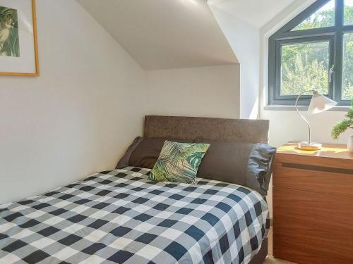 a bedroom with a bed with a checkered blanket at River Lodge Annexe in Rhondda