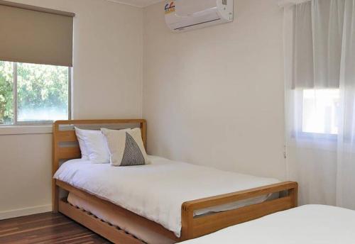 een slaapkamer met een bed met witte lakens en een raam bij ATALLAWA in Amity Point