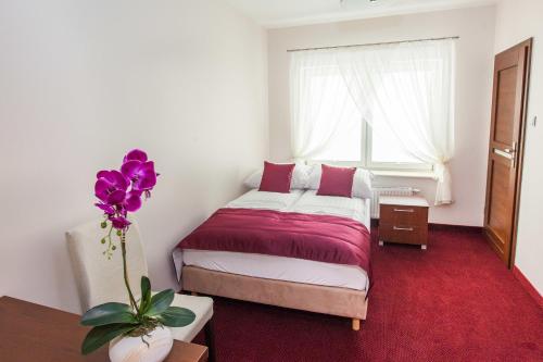 a bedroom with a bed and a vase with purple flowers at Hostel Zambrow in Zambrów