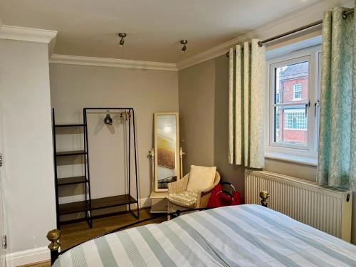 a bedroom with a bed and a chair and a window at 3-bed cottage in Sway, New Forest (5 min walk from Sway Train Station) in Sway