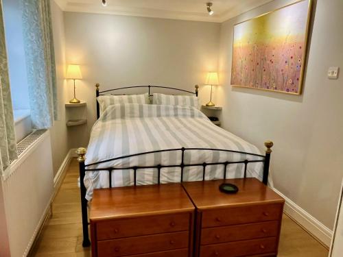 a bedroom with a bed with a wooden dresser and two lamps at 3-bed cottage in Sway, New Forest (5 min walk from Sway Train Station) in Sway
