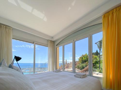 una camera da letto con una grande finestra con vista sull'oceano di Villa l'ensoleillée vue panoramique mer, 250 m de la plage et du centre ville a Mentone