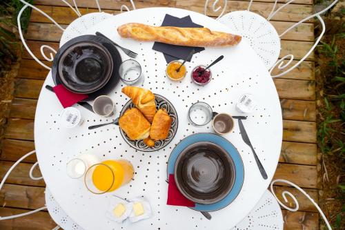 een witte tafel met daarop een bord met ontbijtproducten bij Cottage, Lodge & Spa in Prouilly