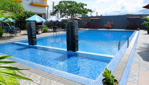 a large blue swimming pool with umbrellas next to a building at Vega Prime Hotel & Convention in Sorong