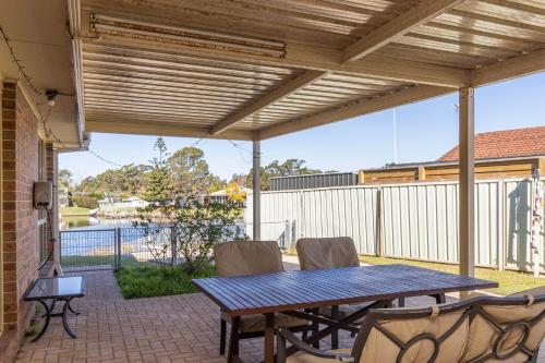 a patio with a wooden pergola and a table and chairs at Holiday on the Water in Sussex inlet