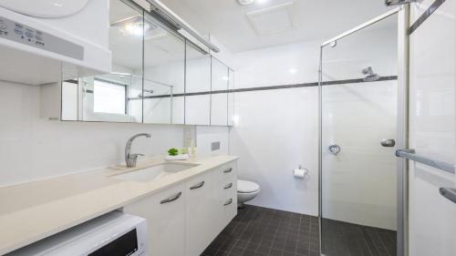 a bathroom with a shower and a sink and a toilet at Waves On Main 20 in Yamba