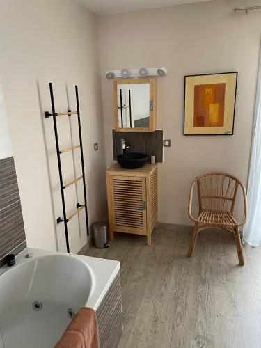uma casa de banho com uma banheira, uma cadeira e um espelho. em La Maison de l'Auzette em Limoges