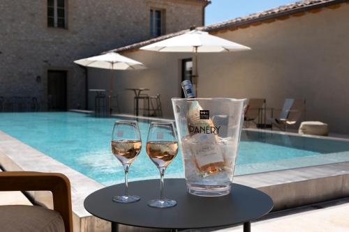 two glasses of wine on a table next to a pool at Domaine de Panery in Pouzilhac