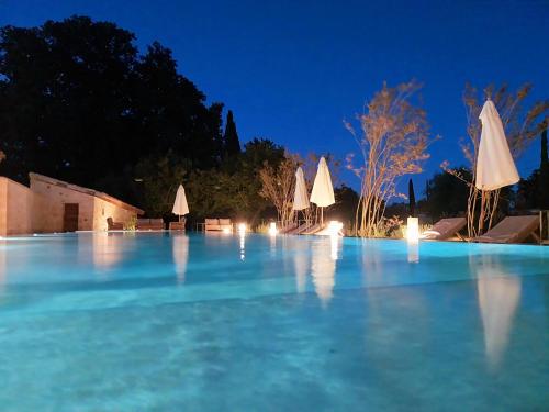 a pool of blue water at night with umbrellas at Domaine de Panery in Pouzilhac