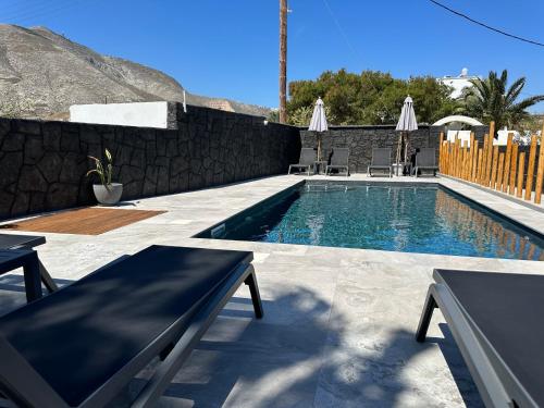 a swimming pool with two benches next to a wall at Dragonfly Villas in Kamari