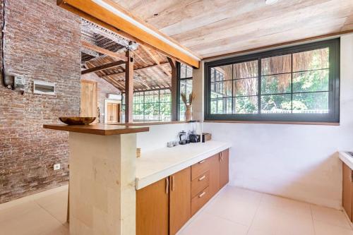 a kitchen with wooden ceilings and a brick wall at The Pink Joglo, a cheerful 3BDR Villa W/Pool and Rice-field view. in Dalung