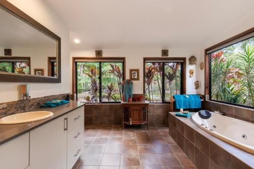 baño con 2 lavabos, bañera y 2 ventanas en Eclectic Oasis in Doonan, Sunshine Coast, en Doonan
