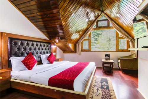 a bedroom with a large bed with red pillows at MHA hotels MOORANG mall manali in Manāli
