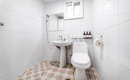 La salle de bains blanche est pourvue de toilettes et d'un lavabo. dans l'établissement Sky Sea Pension, à Yangyang