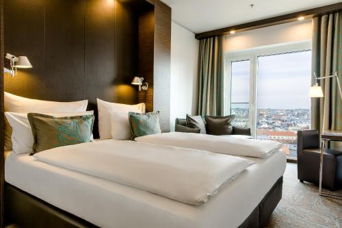 two beds in a hotel room with a window at Motel One Wien-Hauptbahnhof in Vienna